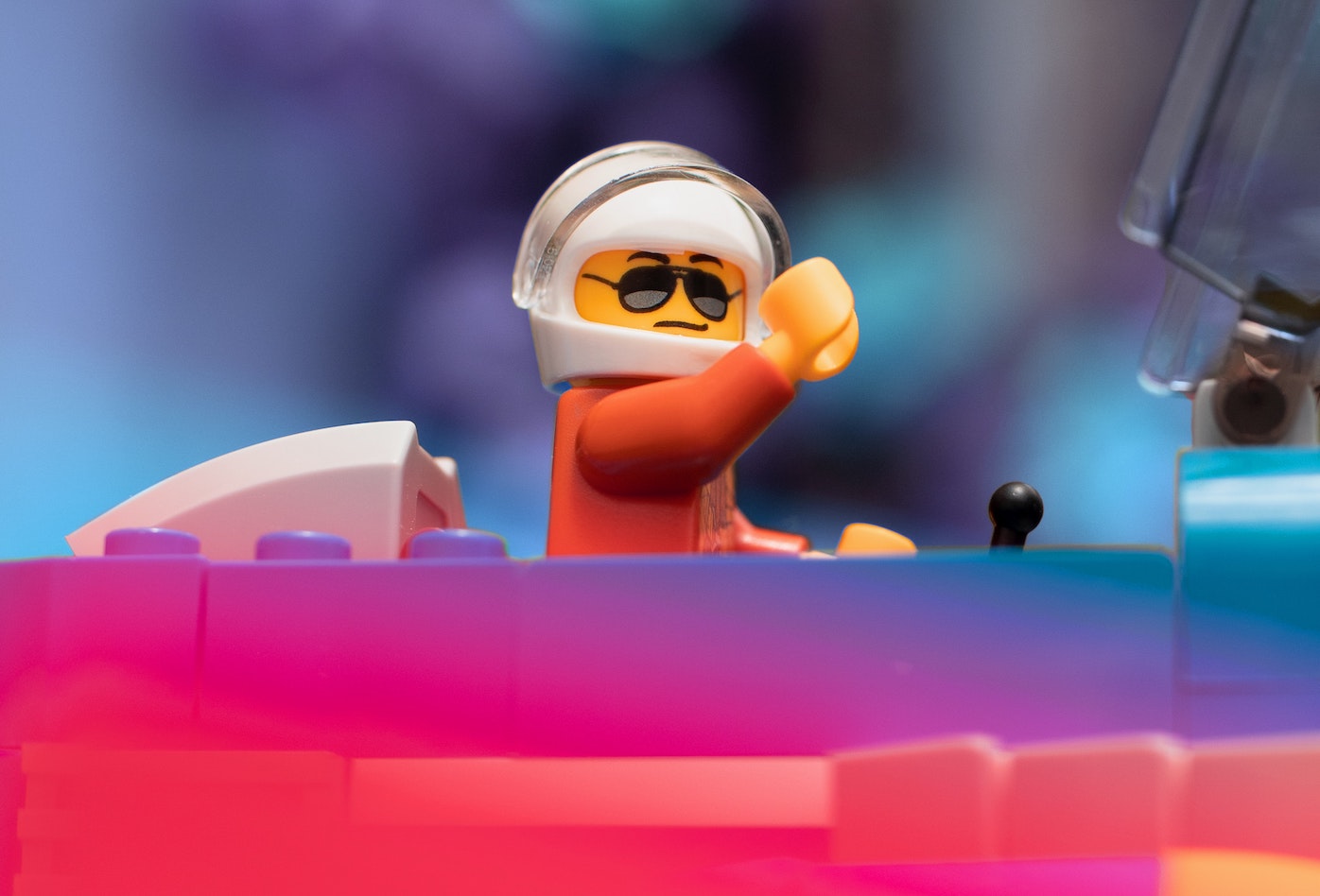 Lego pilot figure in helmet waving from the cockpit of a plane
