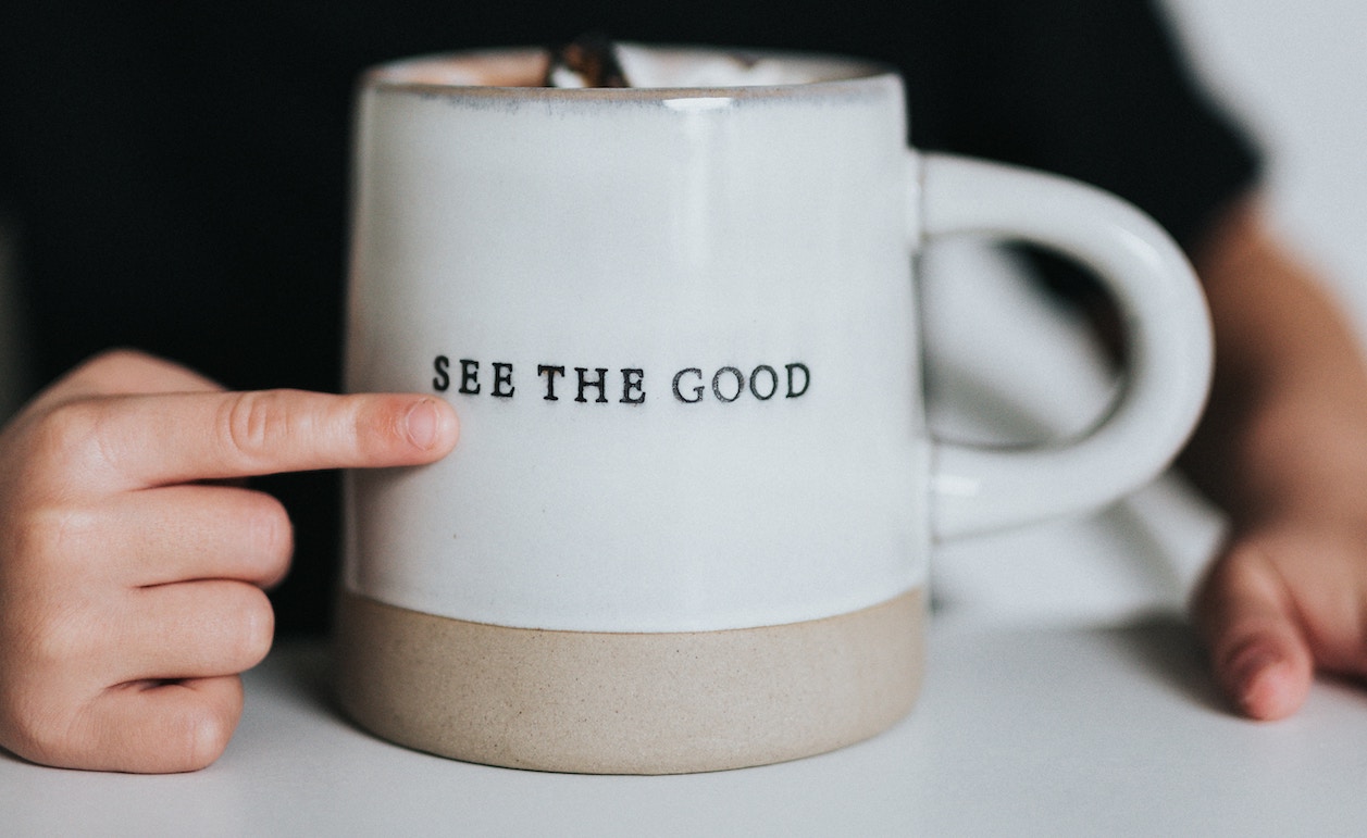 child pointing to a mug with a quote saying "see the good". This is in relation to a blog about The Art Of Giving Constructive Feedback
