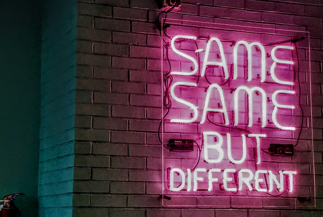Image shows a pink neon sign saying "same, same but different" in the context of this blog about how to handle leadership change in a scaling business.