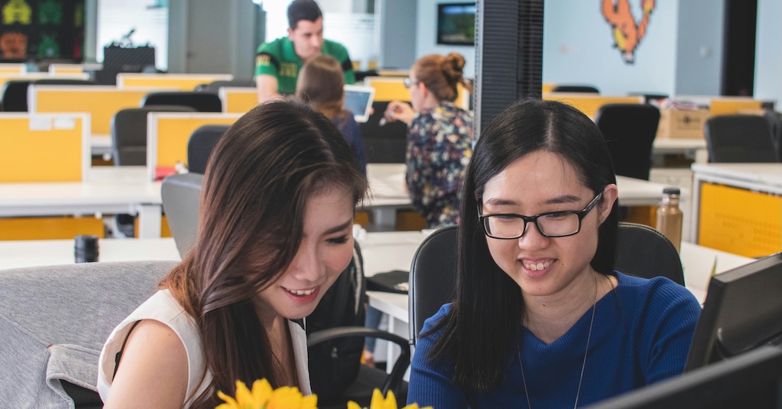 Two women sitting at a computer talking through what they're learning